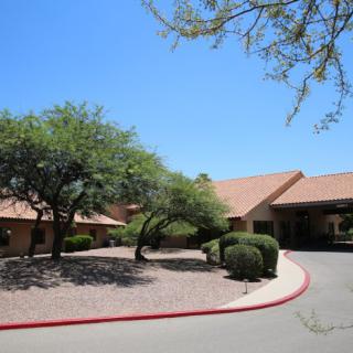 A building with a desert landscape, featuring trees and a driveway.
