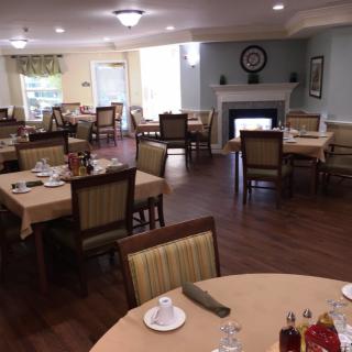 A neatly arranged dining room with several set tables and a fireplace.