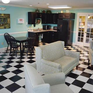 A cozy kitchen and living area with checkered black and white flooring, featuring comfortable seating and modern cabinetry.