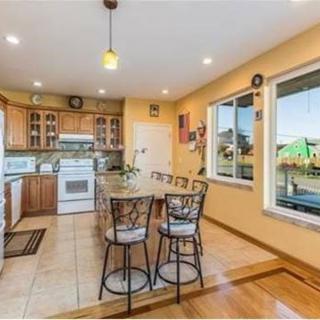 A cozy kitchen with wooden cabinets, a central island with bar stools, and a large window offering ample natural light.