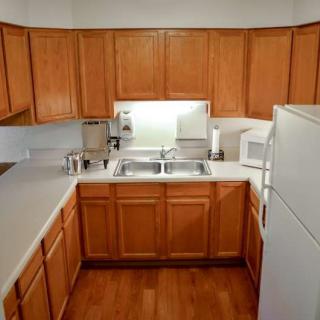 A modern kitchen with wooden cabinets and white appliances, featuring a double sink and ample counter space.