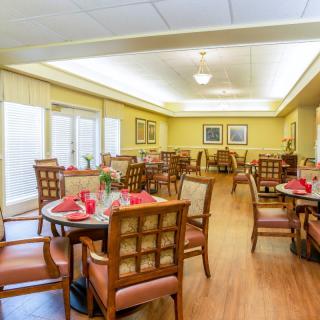 A well-lit dining area with neatly arranged tables and chairs, featuring wooden furniture and tasteful decor.