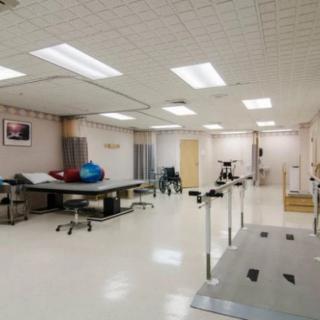 A well-equipped physical therapy room with exercise equipment and treatment tables.
