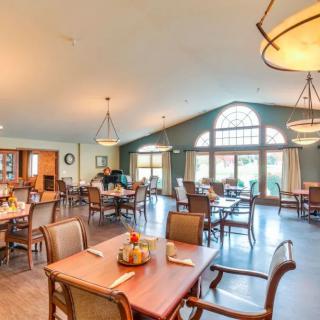 Spacious dining area with wooden tables and large windows letting in natural light.