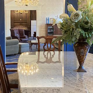 A well-decorated dining area featuring a marble table with an elegant flower arrangement, adjacent to a cozy living room.