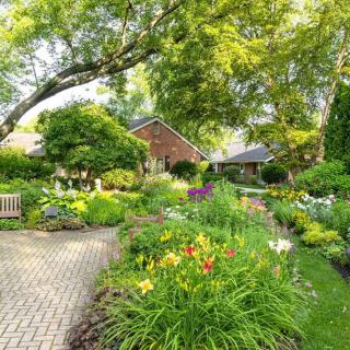 A beautiful garden full of colorful flowers and lush greenery, with a brick pathway leading through the landscape.