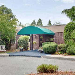 A building entrance with a green awning, surrounded by well-maintained landscaping.