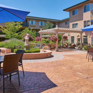 A sunny courtyard with outdoor seating and umbrellas in an apartment complex.