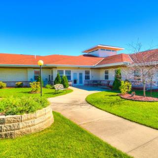 A modern building surrounded by a well-maintained lawn and a winding pathway under a clear blue sky.