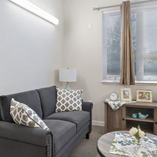 A cozy, modern living room with a gray sofa, patterned cushions, and decorative elements.