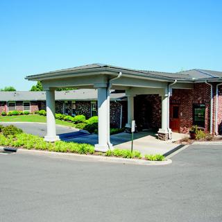 A commercial building entrance with columns and a driveway under a clear blue sky.