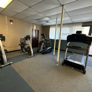 A view of a small indoor gym featuring various exercise equipment including treadmills and ellipticals.