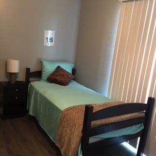 A small, minimalist bedroom with a single bed and a nightstand.