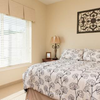 A cozy bedroom with floral bedding and a large window letting in natural light.
