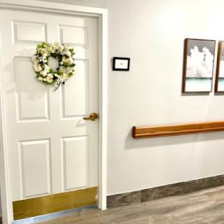 A beautifully decorated door adorned with a wreath, leading into an inviting hallway with framed pictures.