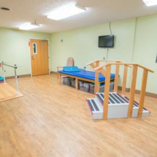 A bright therapy room equipped with exercise tools and a blue treatment table.