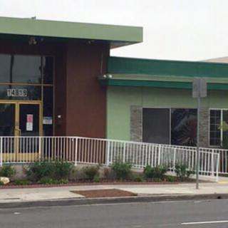 A modern commercial building with a green facade and large windows.