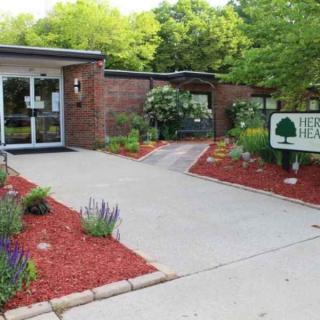 A clinic entrance with landscaped gardens and a sign indicating its name.