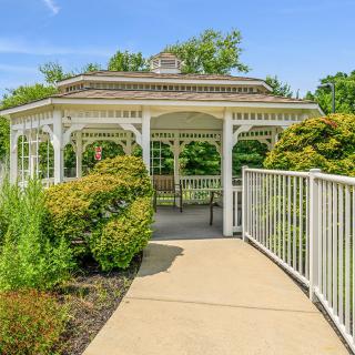 A charming gazebo surrounded by lush greenery and a smooth pathway.