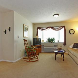 A cozy living room with a sofa, rocking chair, and a television set near the window.