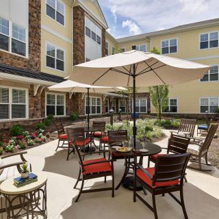 A sunny courtyard with outdoor seating and umbrellas in front of a building.