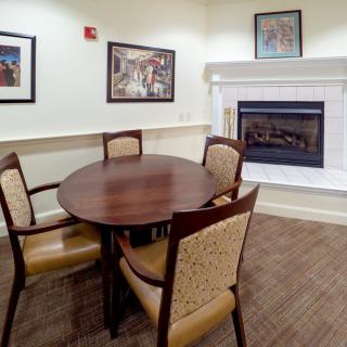 A cozy dining area featuring a round table with four chairs, a fireplace, and framed artwork on the walls.