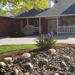 A suburban house with a landscaped front yard featuring rocks and flowering plants.