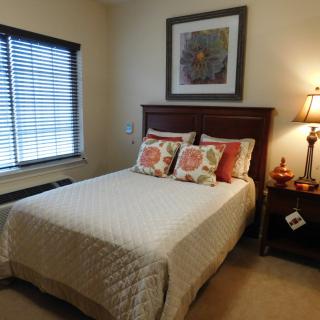 A cozy bedroom with a neatly made bed, decorative pillows, and warm lighting.