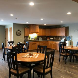 A cozy dining area with wooden tables and chairs adjacent to a kitchen.