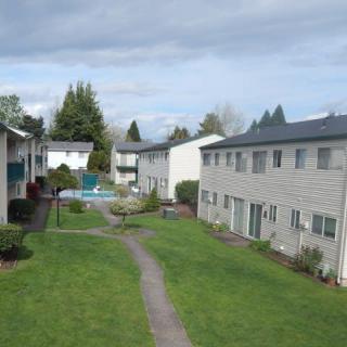 View of an apartment complex with a grassy courtyard and swimming pool.