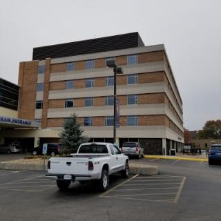 A multi-story hotel with a parking lot in front, under a cloudy sky.