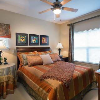 A cozy bedroom featuring a neatly made bed with striped bedding, decorative pillows, and warm lighting.