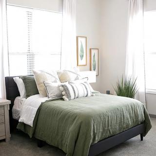 A cozy bedroom with green bedding and stylish decor.