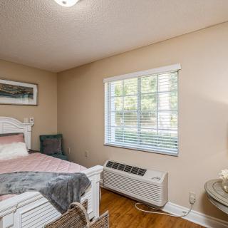 A cozy bedroom with a bed, window, and air conditioning unit.