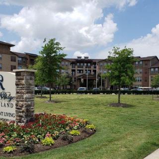 Entrance to a residential apartment complex with landscaped greenery.