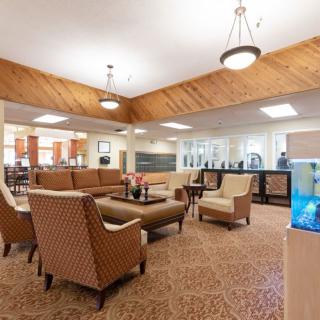A cozy lobby area featuring comfortable seating with sofas and chairs, illuminated by soft overhead lighting.