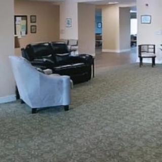 A spacious living room area with sofas and chairs, featuring a carpeted floor.