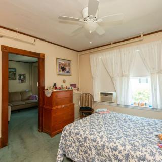 A cozy bedroom with a bed, ceiling fan, and natural light coming through the windows.