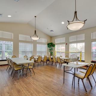 A spacious dining room with multiple tables and chairs, featuring large windows and elegant chandeliers.
