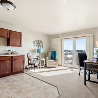 A cozy and well-lit living area featuring a kitchenette, comfortable seating, and access to a balcony.