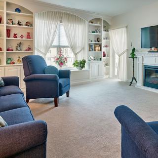 A cozy living room with blue furniture and decorative bookshelves.