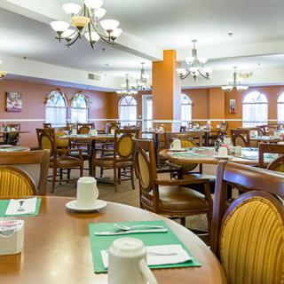 A spacious dining area with neatly arranged tables and chairs, warm lighting, and decorative elements.