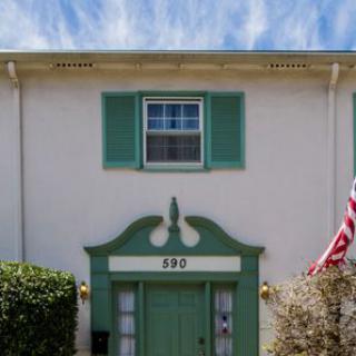 A two-story building with green shutters and an American flag displayed outside.