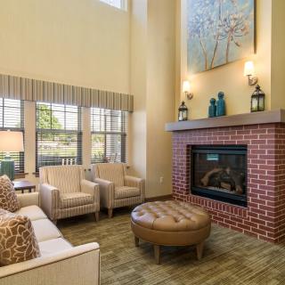 A cozy living room with modern decor, featuring a brick fireplace and comfortable seating.
