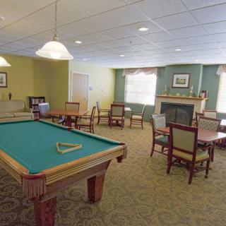 A cozy recreational room featuring a billiard table and a seating area by the fireplace.