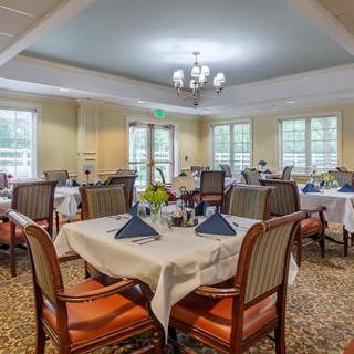 An elegant dining room set with neatly arranged tables and chairs, enhanced by a chandelier.