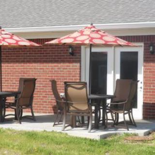 Outdoor patio with tables, chairs, and umbrellas against a brick building.