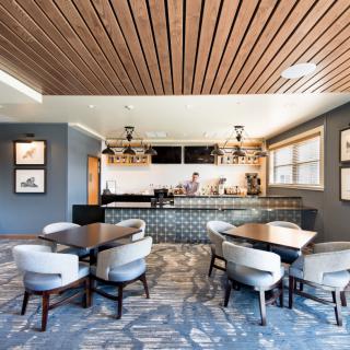 A modern cafe interior featuring a wooden ceiling, elegant seating, and a stylish bar area.