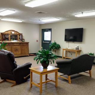 A cozy living room setup featuring two seating areas, a television, and decorative plants.