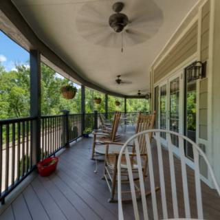 A cozy porch with rocking chairs and ceiling fans overlooking a lush garden.